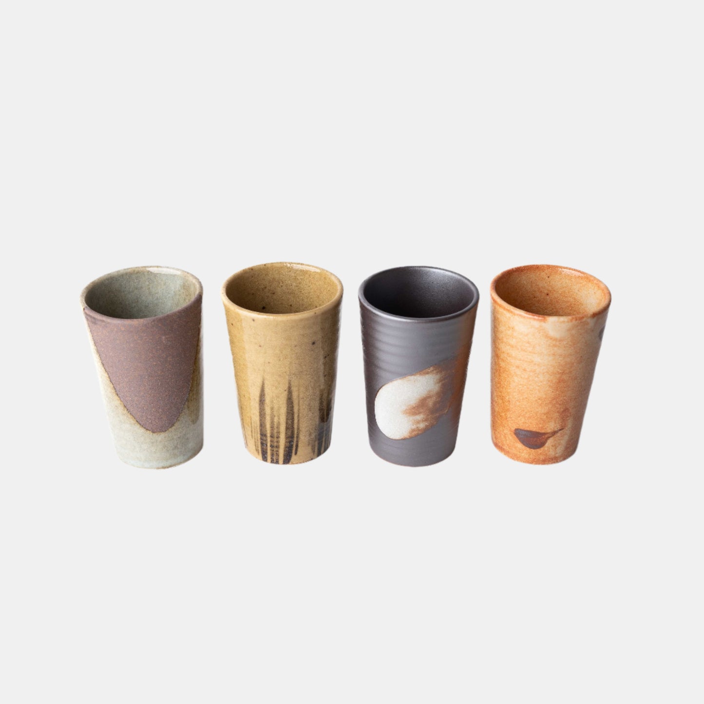 Set of four handmade ceramic cups with straight sides in assorted earthy glazes
