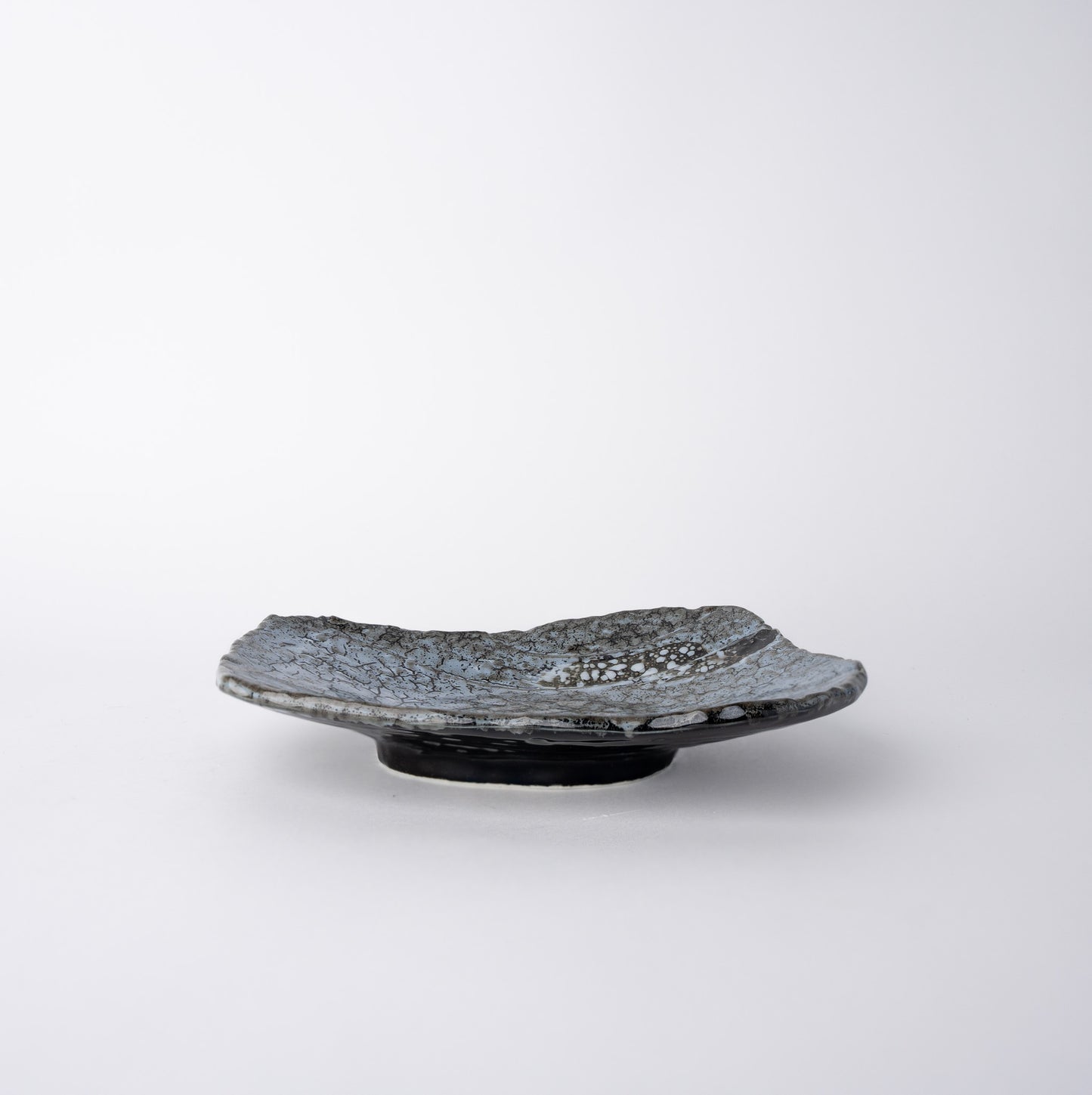 Handcrafted ceramic plate with organic shape and Shiranami grey-blue crackle glaze.
