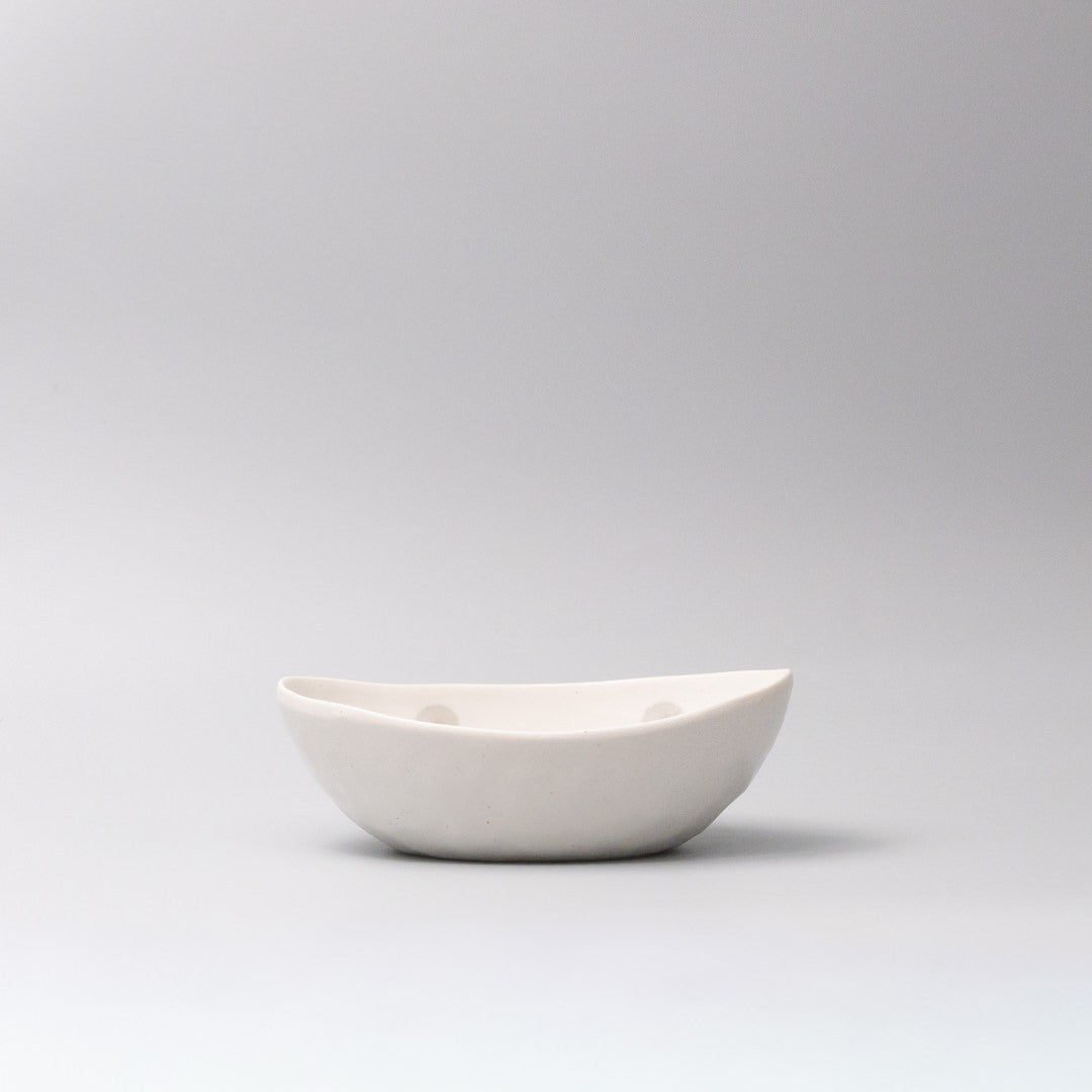 Organic shaped ceramic bowl warm white glaze side view with circular pattern