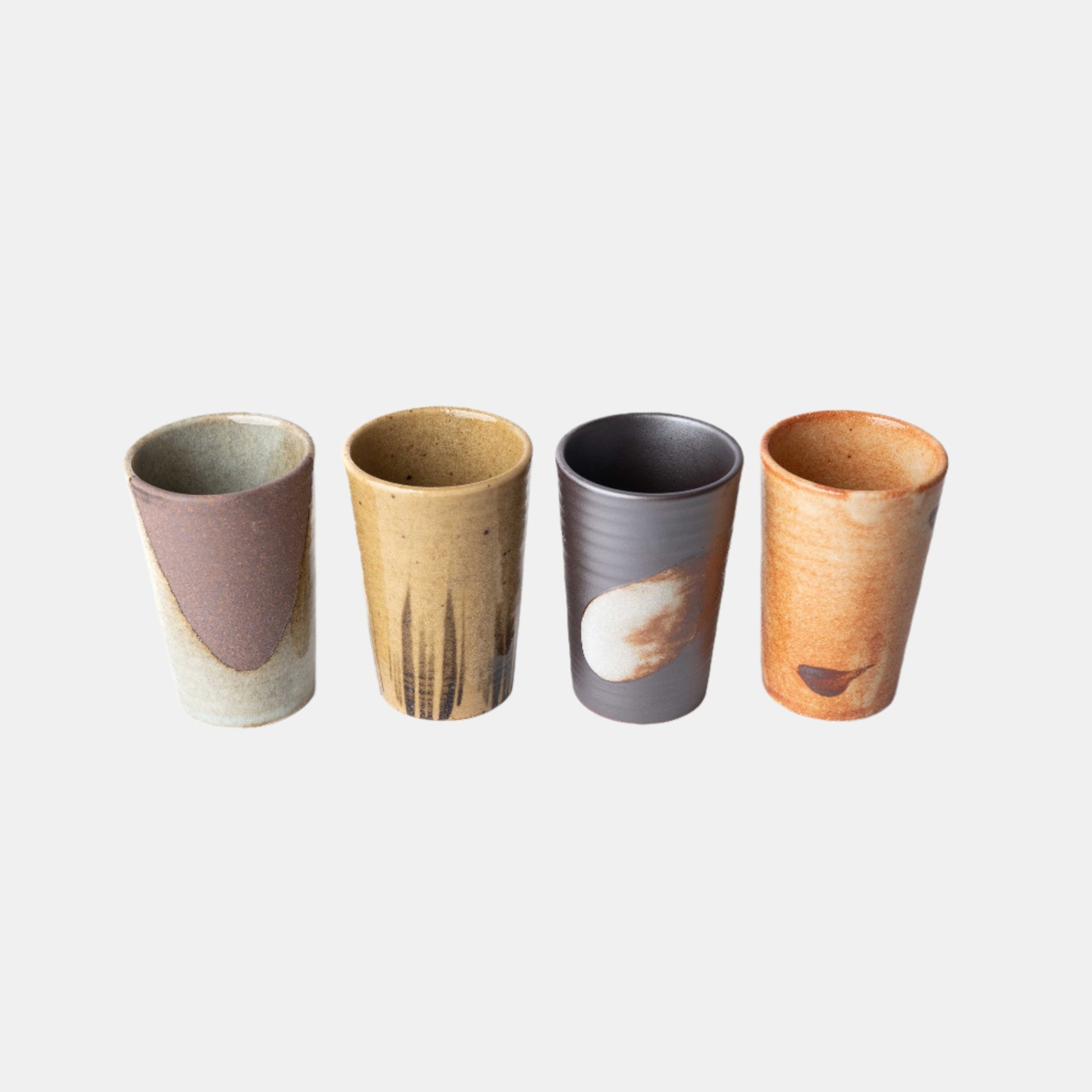 Set of four handmade ceramic cups with straight sides in assorted earthy glazes