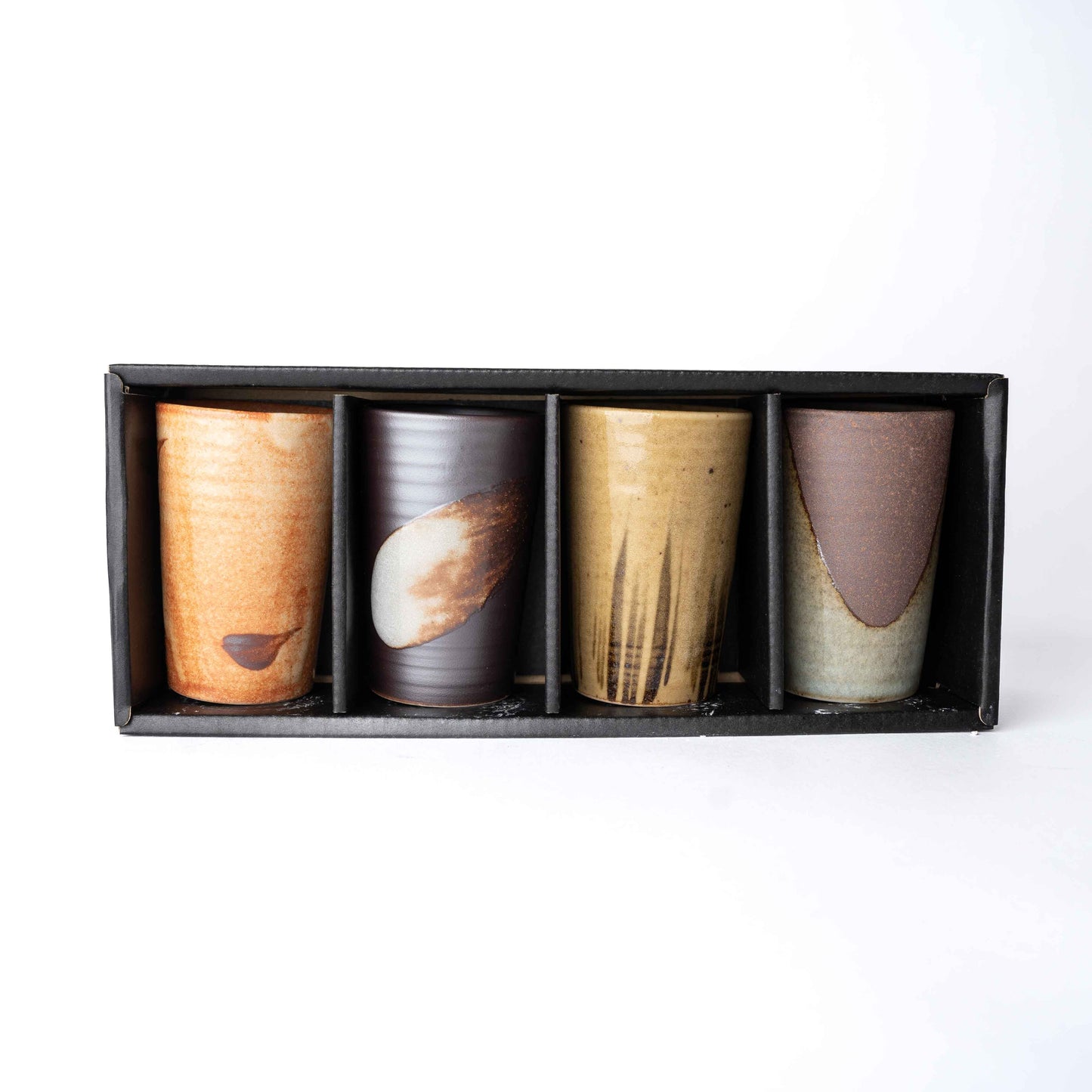 Set of four handmade ceramic cups with straight sides in assorted earthy glazes
