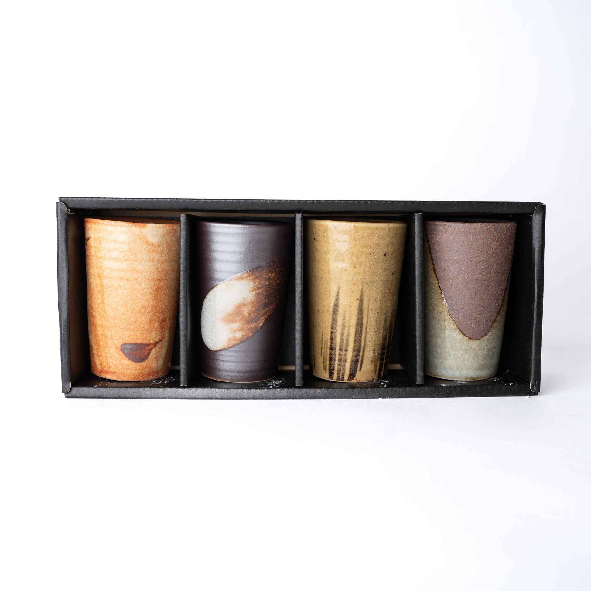 Set of four handmade ceramic cups with straight sides in assorted earthy glazes