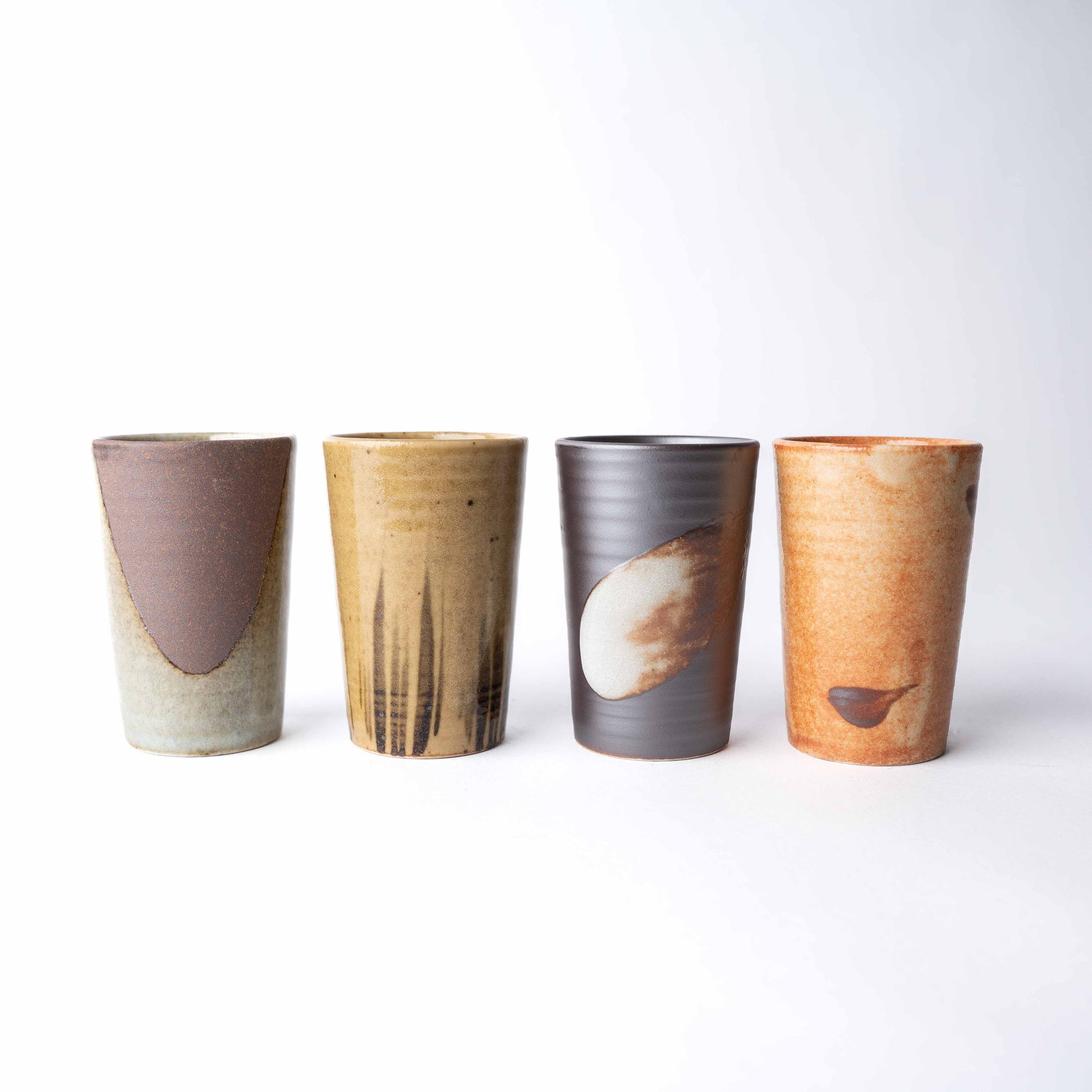 Set of four handmade ceramic cups with straight sides in assorted earthy glazes