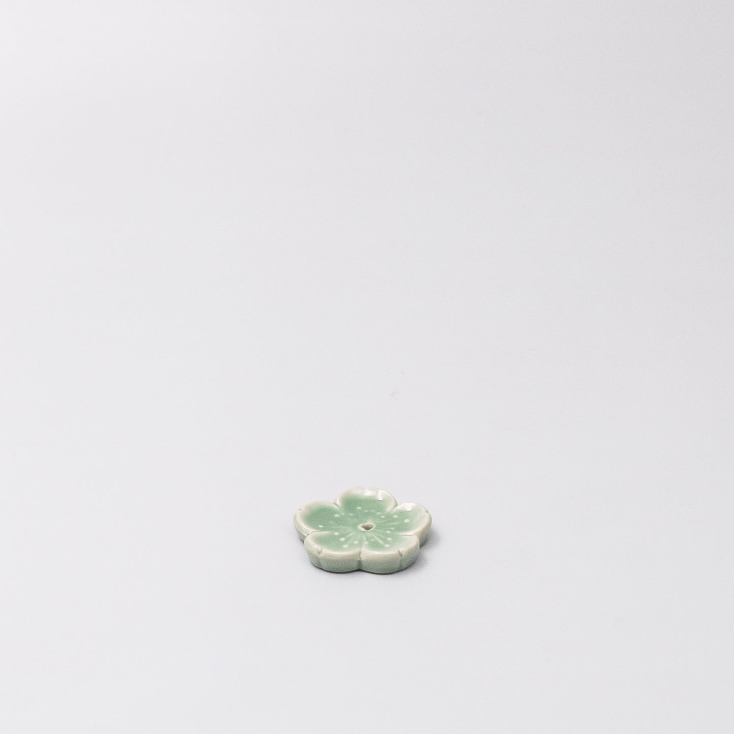 45 degree view of Japanese ceramic incense holder with green Sakura design