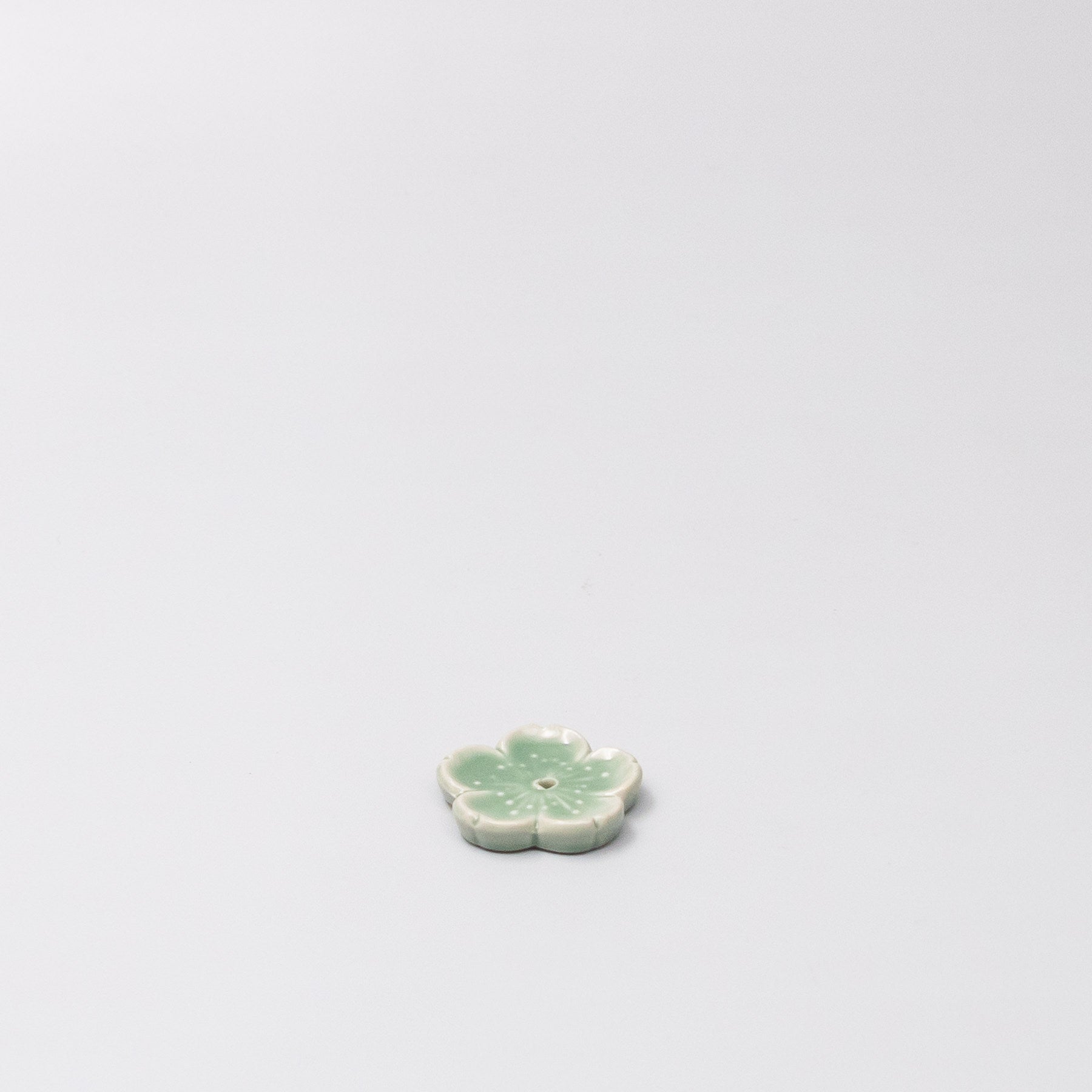 45 degree view of Japanese ceramic incense holder with green Sakura design