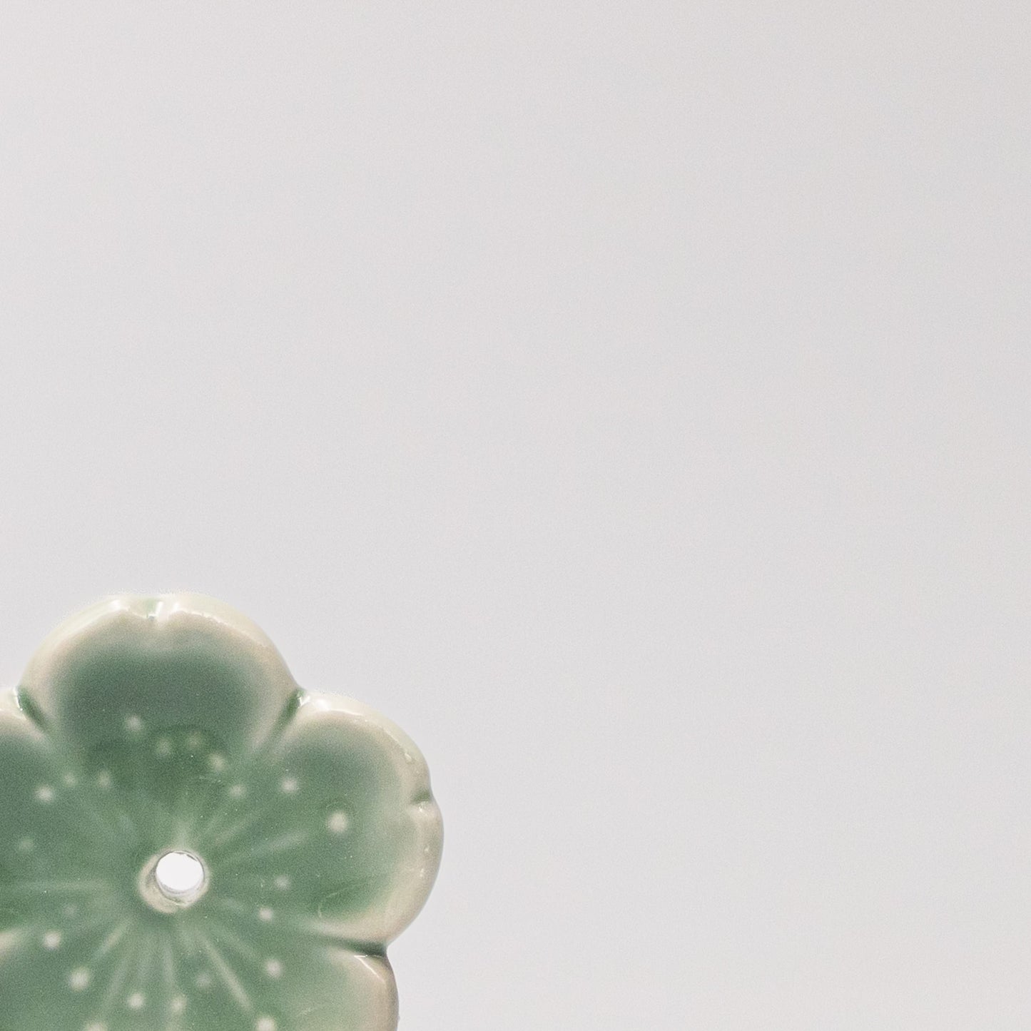 Close up of green Sakura blossom design on Japanese ceramic incense holder