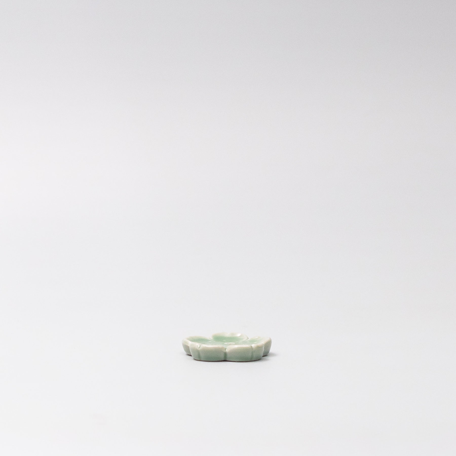 Side view of Japanese ceramic incense holder with green Sakura design